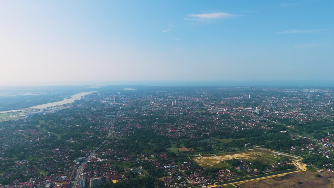 Expansive aerial shot of Kota Bharu, Malaysia, showcasing the cityscape, river, and surrounding greenery under a clear blue sky during the day