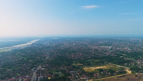 expansive aerial shot of kota bharu, malaysia, showcasing the cityscape, river, and surrounding greenery under a clear blue sky during the day