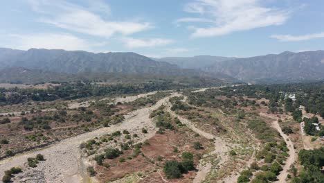 Aerial-wide-rising-shot-of-the-dried-riverbed-of-the-Ventura-River-in-Ojai-Valley,-California