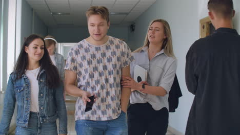 a group of students walk along the corridor of the university school college communicate talk and smile. a large group of people walking in the hall of an educational institution with books in their hands.