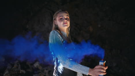 una mujer quemando una bomba de color en un primer plano de la fiesta de la noche.