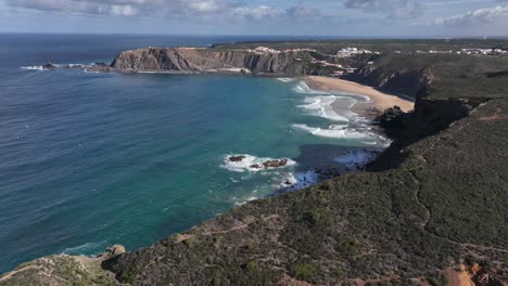 toma aérea volando sobre acantilados verdes que rodean una hermosa bahía junto al océano