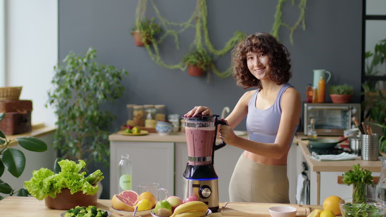 Ritratto di una bella ragazza sportiva che prepara un frullato a casa