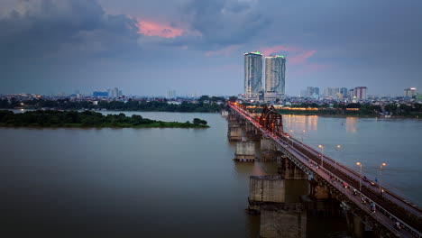 largo puente bien a través del río rojo con el horizonte de hanoi iluminado con luz nocturna al atardecer, vista aérea