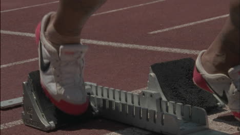 a male runner steps into the blocks and prepares to race