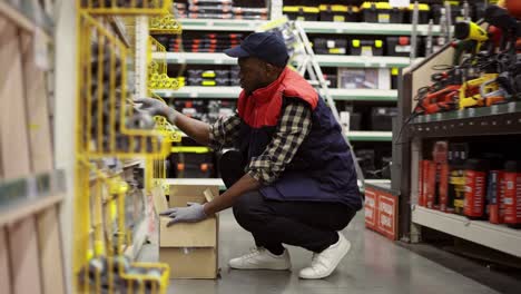 Male-worker-refill-goods-on-lower-shelves-of-hardware-store