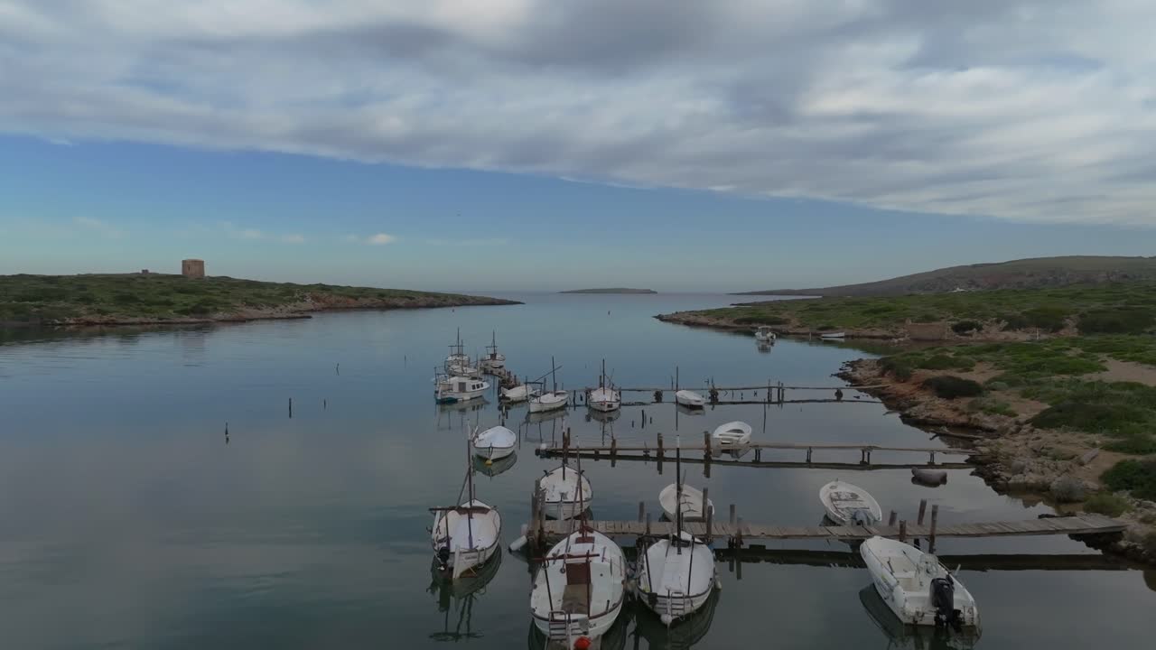 Fishing boats moored in natural harbour port Colom Island Menorca Spain aerial drone