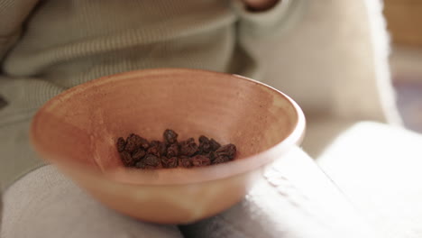an engrossed child on a sofa picks up raisins to eat as they watch tv or film