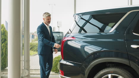 un hombre de negocios examinando un nuevo suv en una sala de exposiciones.