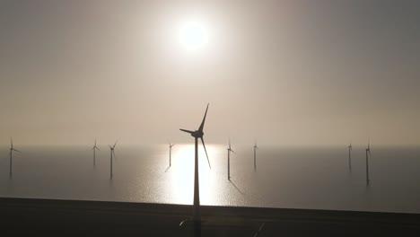 aerial towards wind turbines spinning on epic windpark on sea with bright sunlight, renewable enery