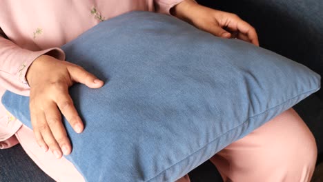 woman sitting with a blue pillow on her lap