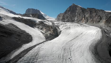 aerial flyover over the allalin glacier with allalinhorn peak in view near saas-fee in valais, switzerland on a sunny summer day in the swiss alps