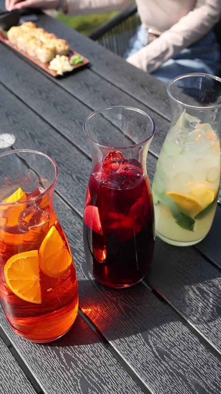 Tres bebidas refrescantes y coloridas con fruta y hielo en una mesa al aire libre