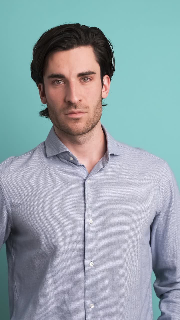 Serious man looking at camera in blue studio