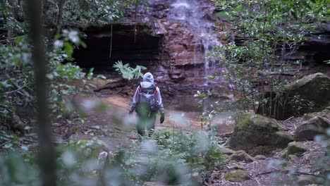 chica indígena australiana caminando a una hermosa cascada escénica en lo profundo del parque nacional de las montañas azules