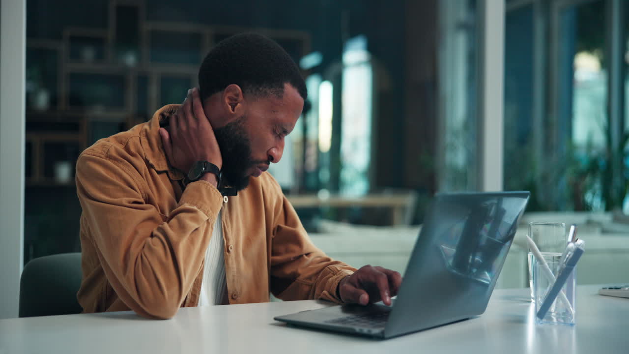 Man experiencing neck pain while working on laptop