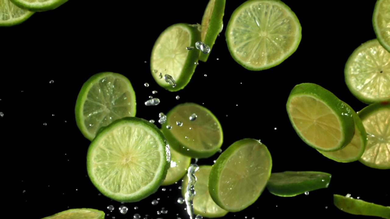 Friske limeskiver falder med vandsprøjt i slowmotion