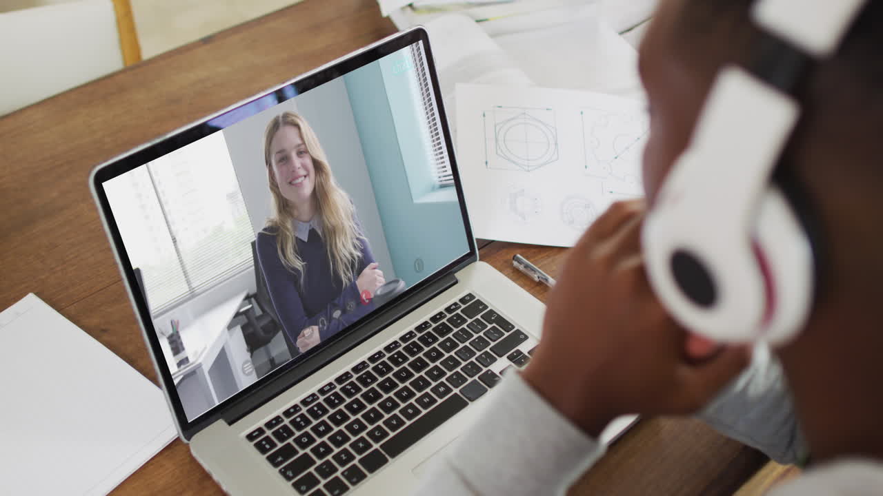 African american businessman sitting at desk using laptop having video call with female colleague