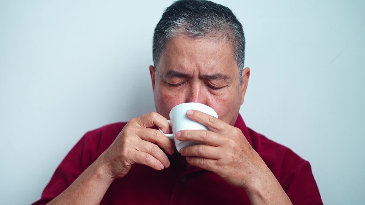 Close up Mature asian man enjoying comforting warm beverage savoring