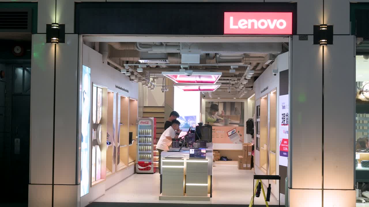 Chinese customers are seen inside a Lenovo store, while pedestrians walk past the store at night in Hong Kong.