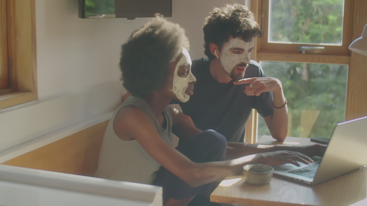 Coppia con maschere per il viso che chatta e usa il laptop a casa