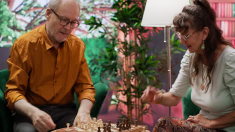 pareja de ancianos disfrutando de una competencia de juego de ajedrez para el ocio en casa