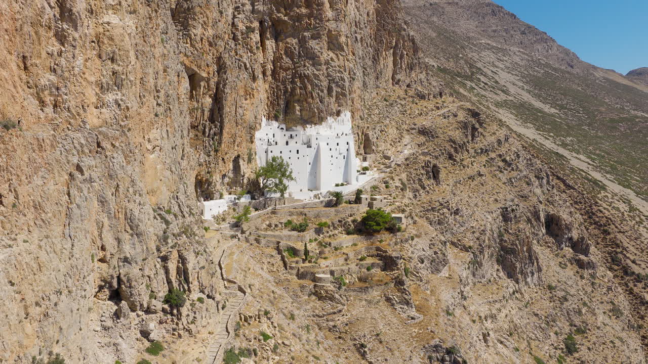Hozoviotissa Monastery clinging to cliffs above sea on Amorgos Island, Greece, aerial ascend establish