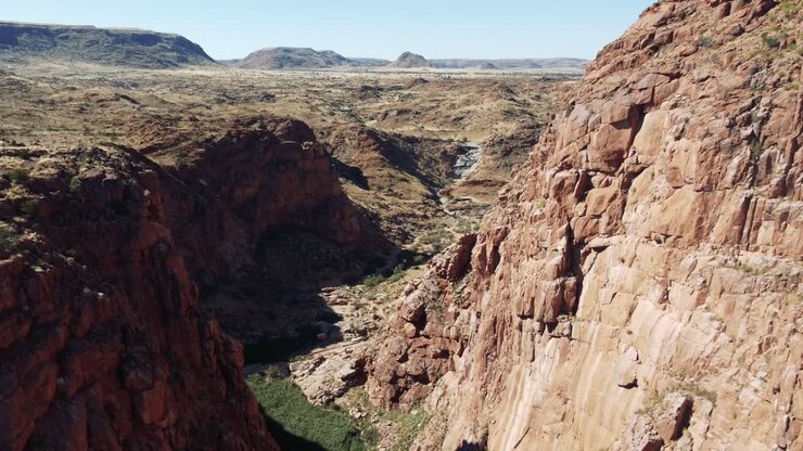 Ripresa in discesa con drone in una gola lussureggiante tra scogliere presso le sorgenti termali di Riemvasmaak in Sudafrica, vicino alla Namibia, lungo il fiume Orange