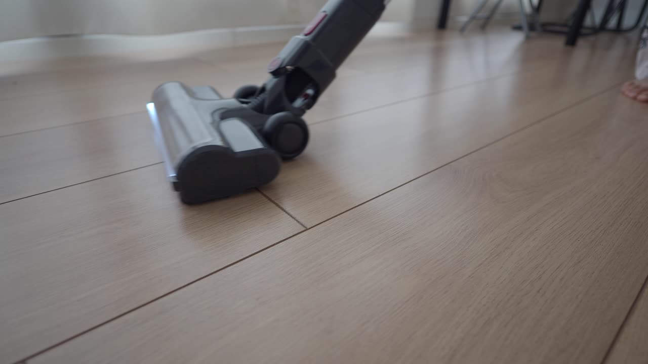 Cabeça de aspirador de pó limpando piso de madeira com luz