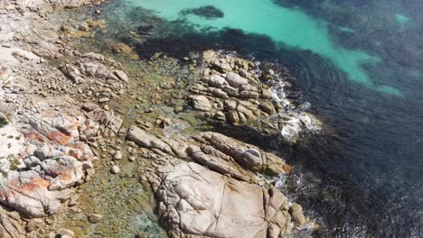 Drone-aerial-pan-up-over-beach-with-tropical-blue-water-to-reveal-forest-and-park