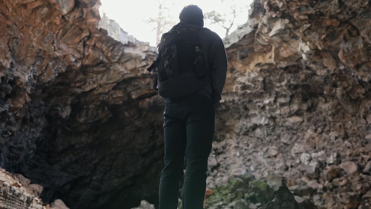 panorámica hasta el hombre mirando la gran abertura en la cueva en el monumento nacional el malpaís