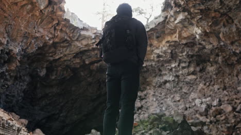 panorámica hasta el hombre mirando la gran abertura en la cueva en el monumento nacional el malpaís