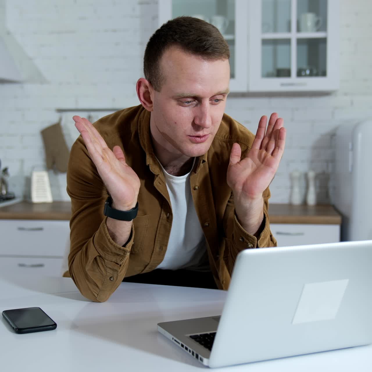 Young man having a video conversation on kitchen background. Freelancer working online on wireless computer at home. Remote business