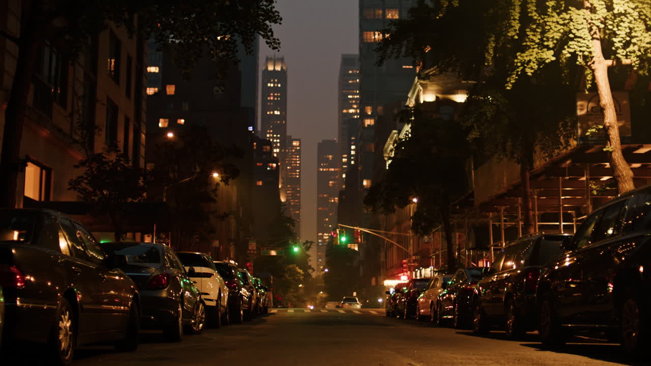 카메라는 밤에 산불의 연기가  ⁇ 인 뉴욕 시의 거리를 가로질러 이동합니다.