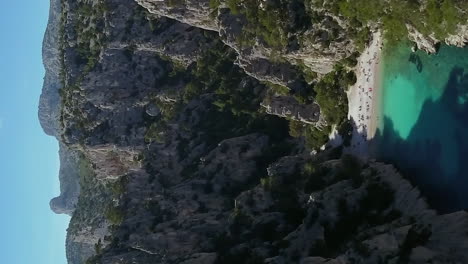 The-remote-and-secluded-Calangue-d'En-Vau-beach-beneath-cliffs-near-Cassis,-France---aerial-vertical-view