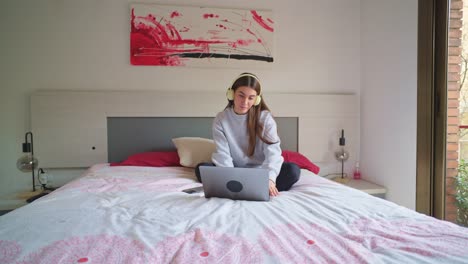 mujer trabajando en una computadora portátil en el dormitorio