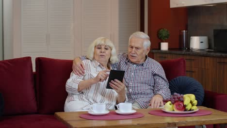 Pareja-De-Abuelos-Mayores-Hablando-Y-Usando-Una-Tableta-Digital-En-Casa.-Cierre-De-Emergencia-Por-Coronavirus