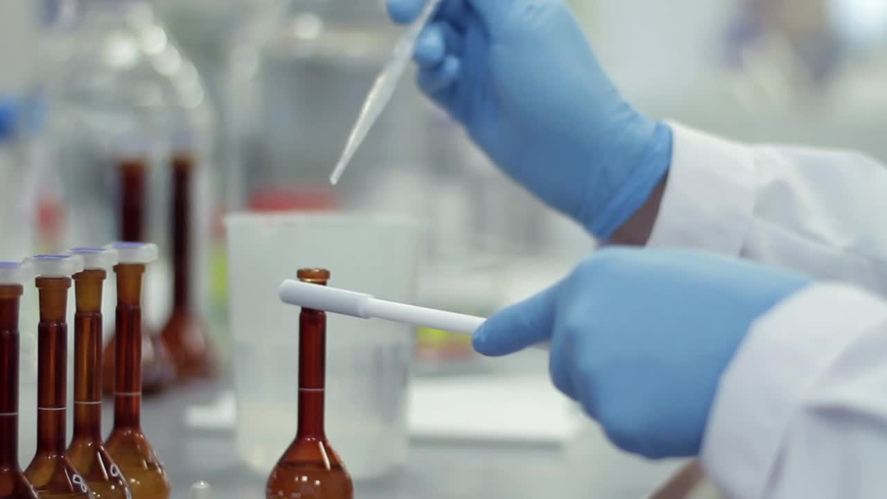 Scientist in Gloves Pipetting Liquid into Flask in Laboratory