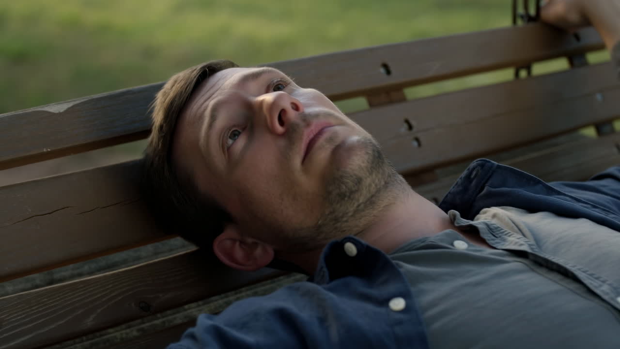 Man Lying On Park Bench, Gazing Skyward, Casual Shirt And Light Stubble, Slow Swing Motion, Evening Light