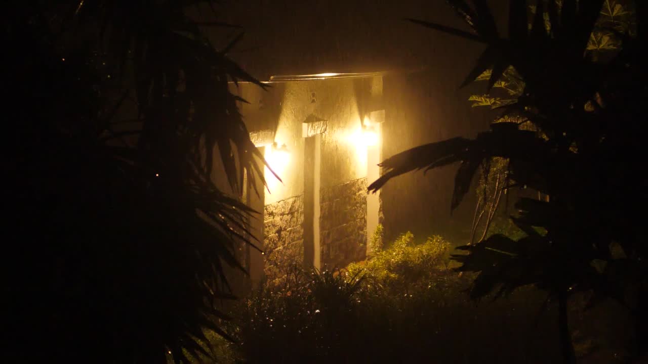 Duas lâmpadas incandescentes iluminam um edifício rural durante uma tempestade tropical no Havaí.
