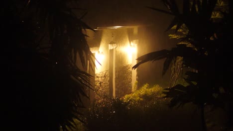 two incandescent lightbulbs light up rural building during a tropical rain storm in hawaii