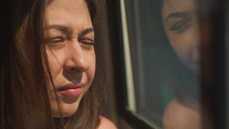 una mujer con los ojos ceñidos se aleja de la ventana del barco en un día soleado de primer plano. el pasajero sufre de la incomodidad de la luz solar brillante. vela de yate