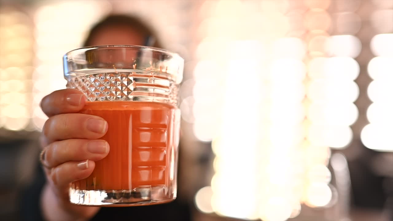 Mujer sosteniendo un vaso de zumo de zanahoria en un restaurante
