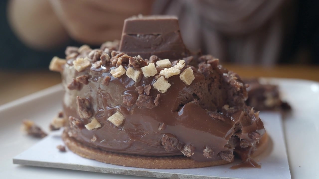 Persona che mangia un dessert al cioccolato con una forchetta di legno