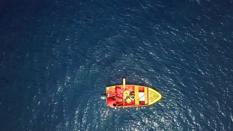 overhead view of a fisherman in his red boat on a sunny day, shores of curacao, dutch caribbean island