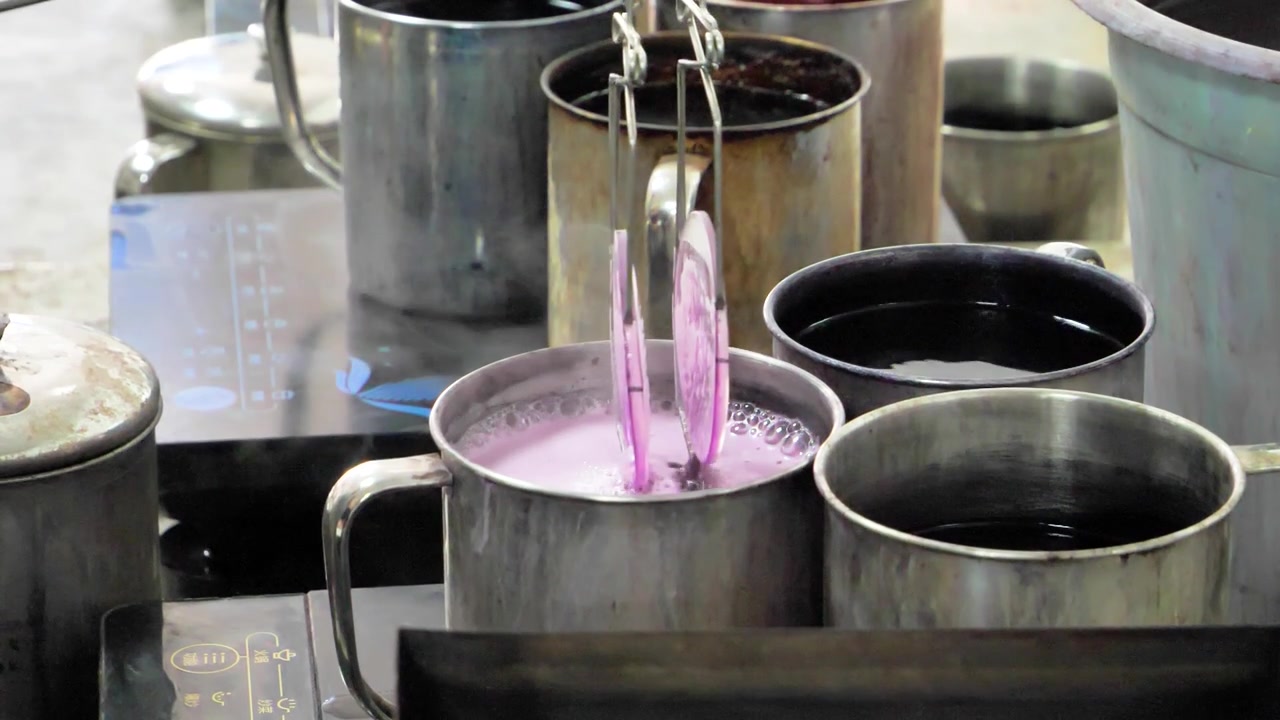 Un operaio applica manualmente una tinta sfumata con prodotti chimici alle lenti in una fabbrica. Provincia di Jiangsu, Cina
