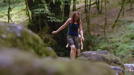 mother and child hiking in a forest stream