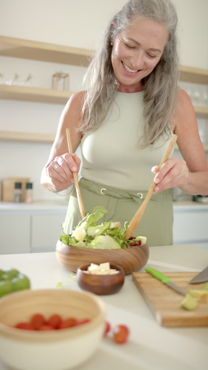 Vertical video: Preparing fresh salad, woman mixing ingredients in kitchen at home