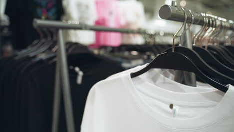 a clothing store, showcasing neatly hung white and black shirts on hangers. highlights the organized display and variety of apparel in a modern retail environment