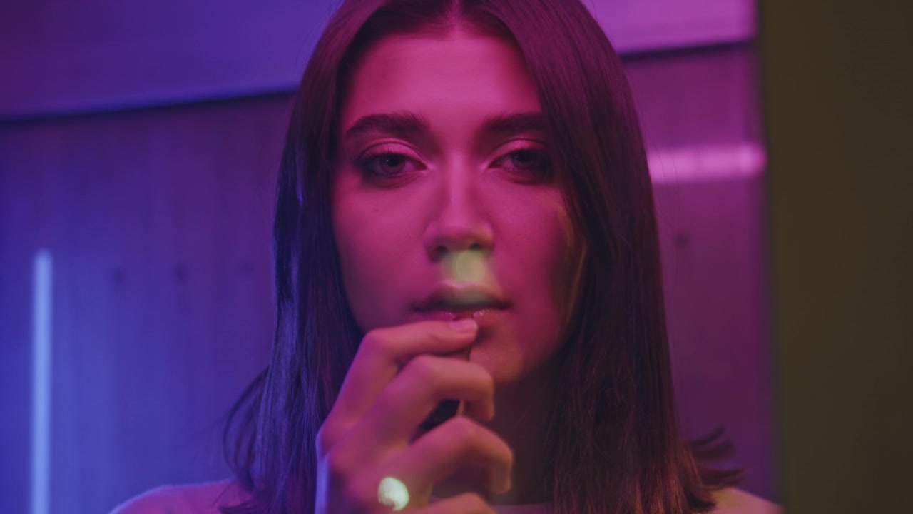 Donna sensuale che si tocca le labbra sotto una luce neon rosa. Ritratto ravvicinato del viso, vita notturna.
